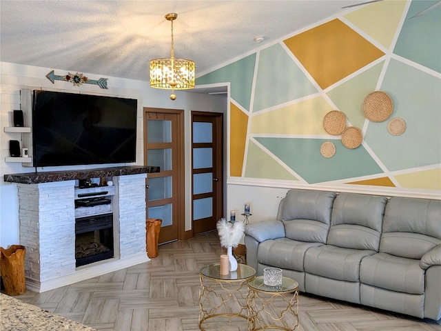 living room featuring parquet flooring, a fireplace, a textured ceiling, and a notable chandelier