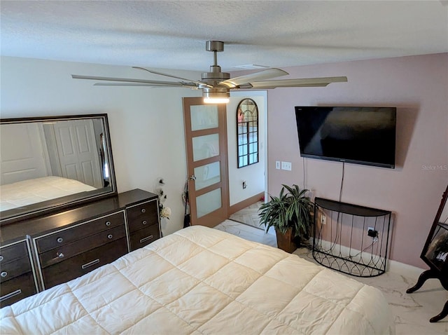 bedroom with ceiling fan and a textured ceiling