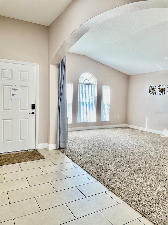 carpeted entryway featuring lofted ceiling