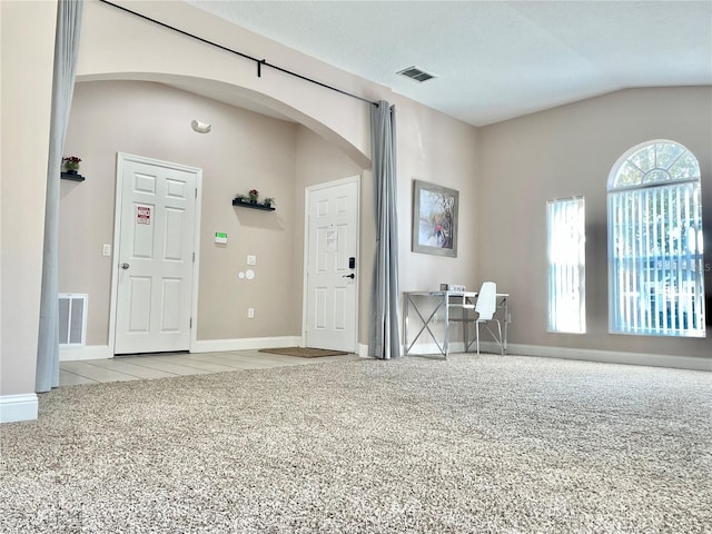 interior space featuring lofted ceiling, light colored carpet, and a textured ceiling