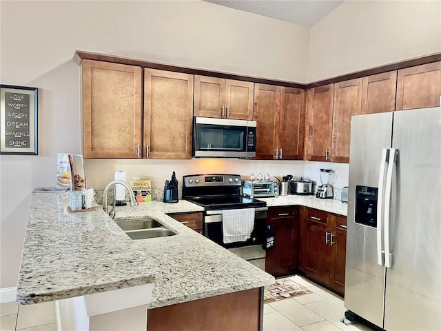 kitchen featuring appliances with stainless steel finishes, sink, light tile patterned floors, light stone counters, and kitchen peninsula