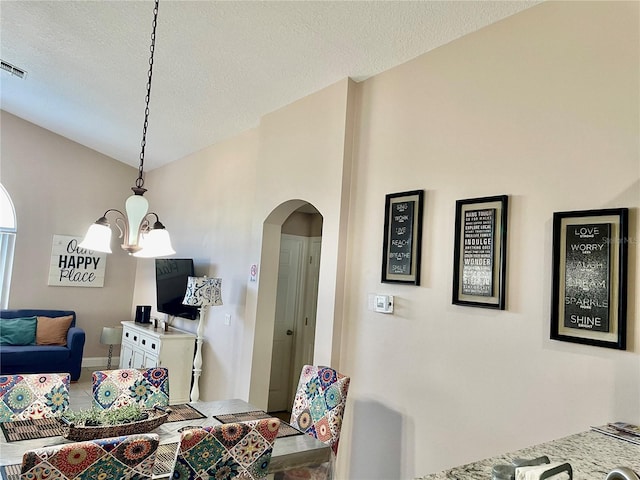 dining room with lofted ceiling, a textured ceiling, and a chandelier