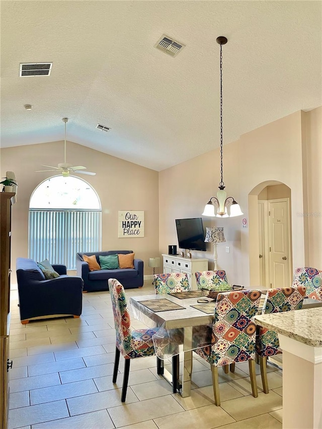 dining room featuring lofted ceiling, ceiling fan with notable chandelier, and a textured ceiling