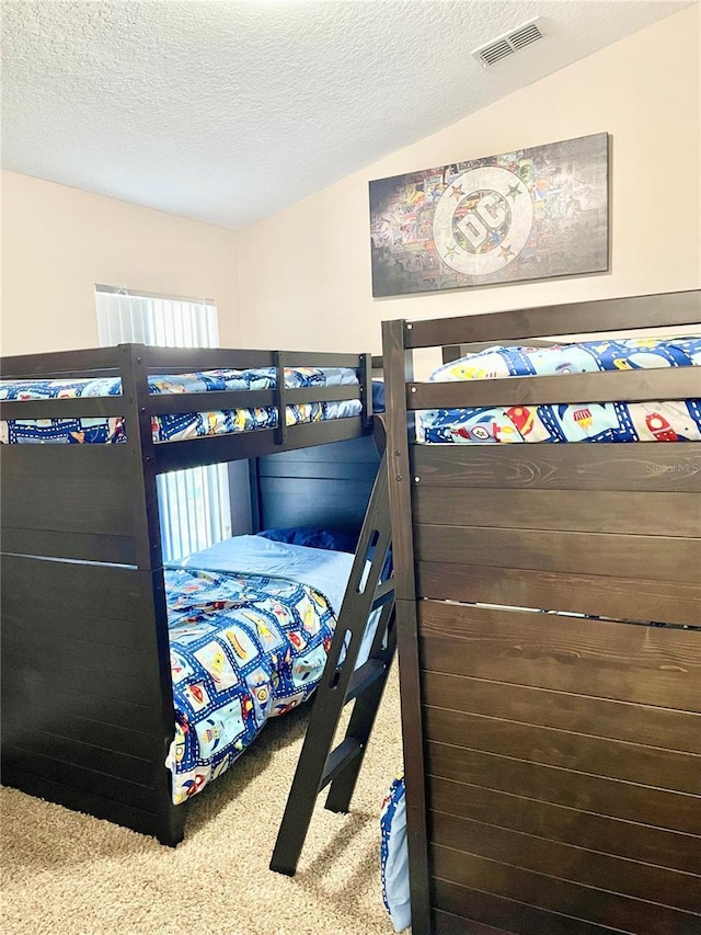 bedroom featuring lofted ceiling, carpet, and a textured ceiling