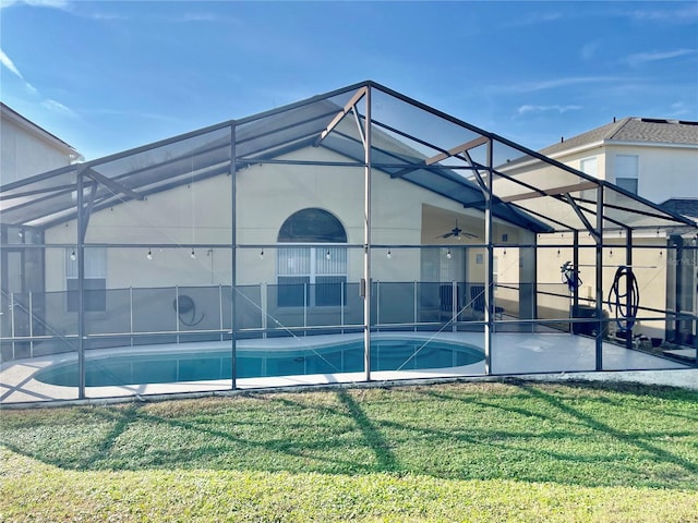 rear view of property with a patio area, a lawn, ceiling fan, and glass enclosure