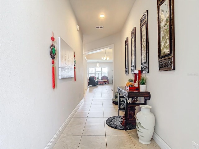 hall featuring a notable chandelier and light tile patterned floors