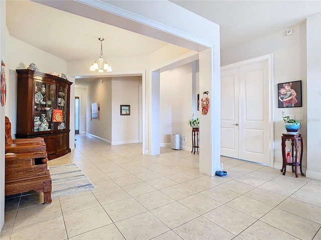 corridor featuring light tile patterned floors and an inviting chandelier