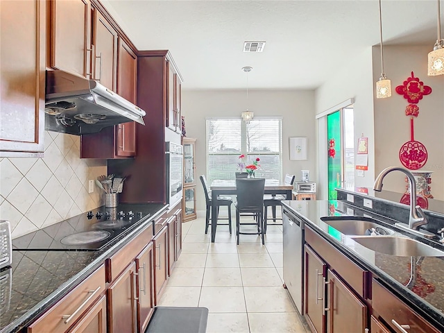 kitchen with sink, tasteful backsplash, decorative light fixtures, light tile patterned floors, and appliances with stainless steel finishes