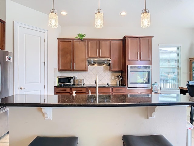 kitchen with appliances with stainless steel finishes, a kitchen breakfast bar, and decorative light fixtures