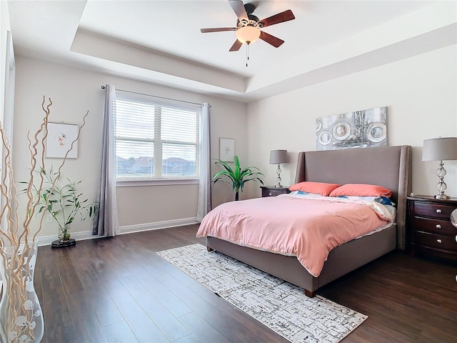 bedroom featuring dark hardwood / wood-style floors, ceiling fan, and a tray ceiling