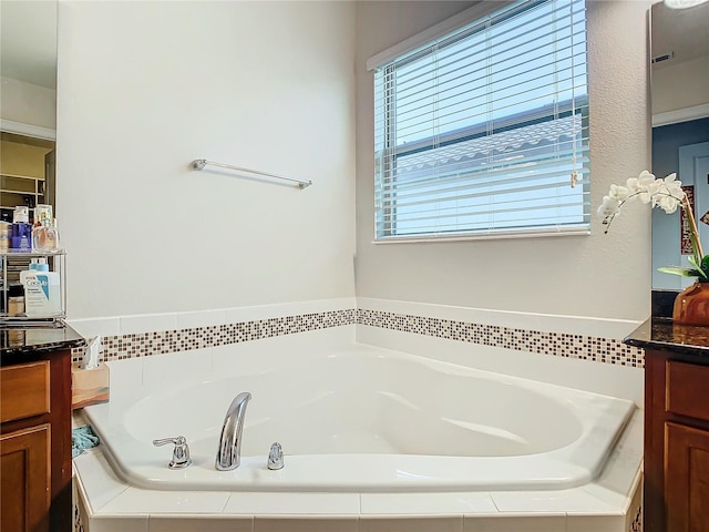 bathroom featuring a relaxing tiled tub and vanity