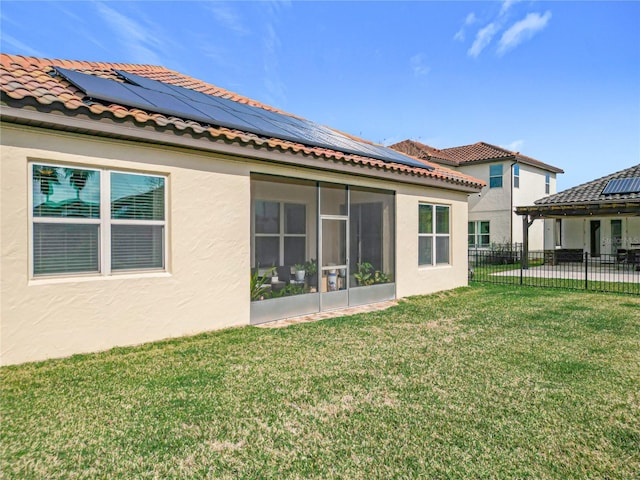 rear view of property with solar panels, a sunroom, and a lawn