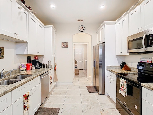 kitchen with light stone counters, stainless steel appliances, sink, and white cabinets