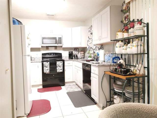 kitchen featuring white cabinetry, light stone countertops, black appliances, and light tile patterned flooring