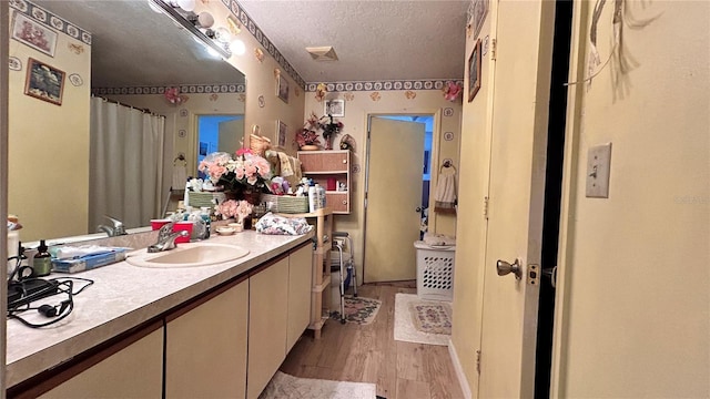 bathroom with vanity, hardwood / wood-style floors, a textured ceiling, and walk in shower