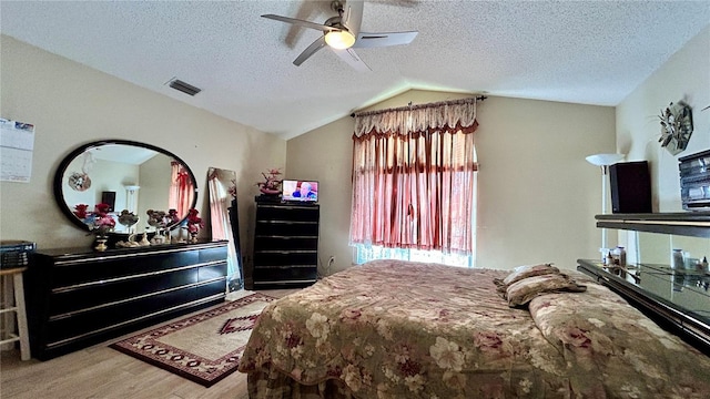 bedroom with ceiling fan, lofted ceiling, light hardwood / wood-style floors, and a textured ceiling