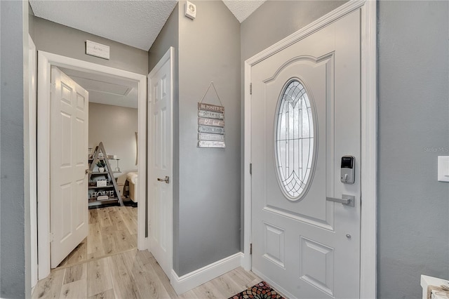 foyer entrance featuring a textured ceiling and light hardwood / wood-style flooring