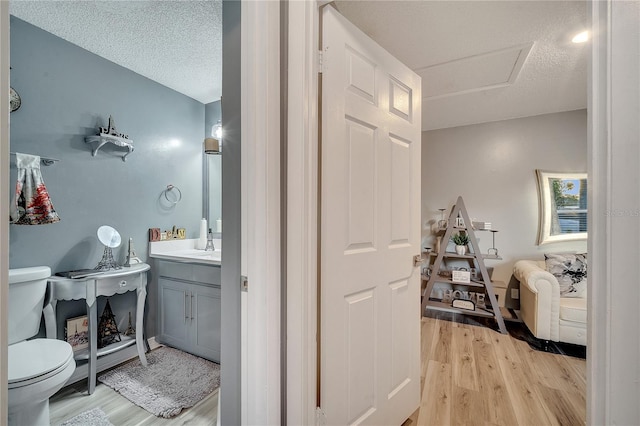 bathroom with vanity, toilet, hardwood / wood-style floors, and a textured ceiling