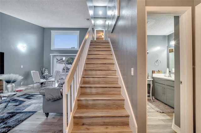 stairway featuring sink, hardwood / wood-style flooring, and a textured ceiling