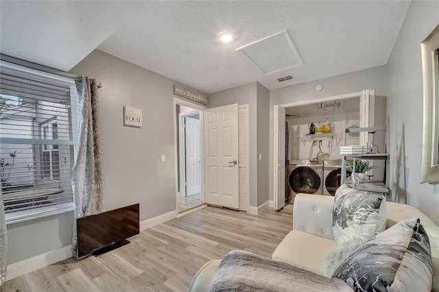 living room with a textured ceiling, washer and dryer, and light hardwood / wood-style flooring