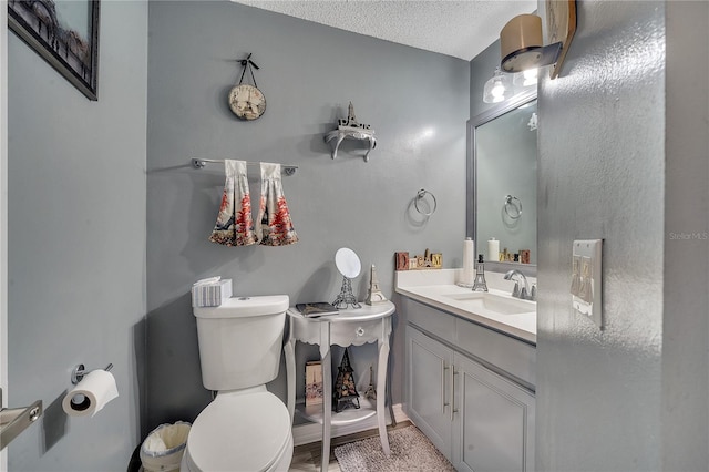 bathroom with vanity, a textured ceiling, and toilet