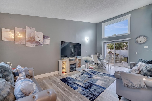 living room featuring a high ceiling, a textured ceiling, and light wood-type flooring