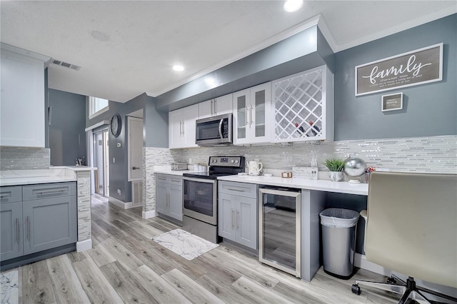 kitchen with gray cabinets, tasteful backsplash, appliances with stainless steel finishes, and beverage cooler