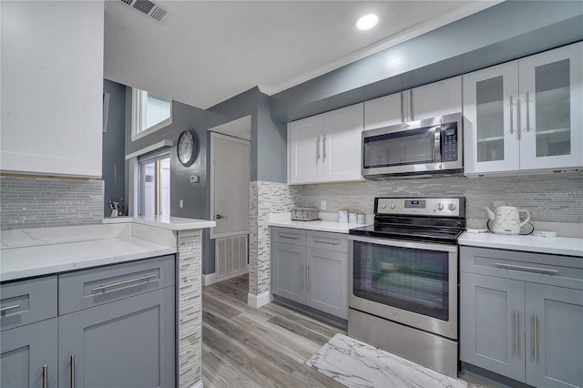 kitchen featuring white cabinetry, appliances with stainless steel finishes, gray cabinets, and light hardwood / wood-style flooring