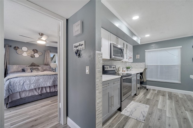 kitchen featuring appliances with stainless steel finishes, white cabinets, decorative backsplash, light hardwood / wood-style floors, and crown molding