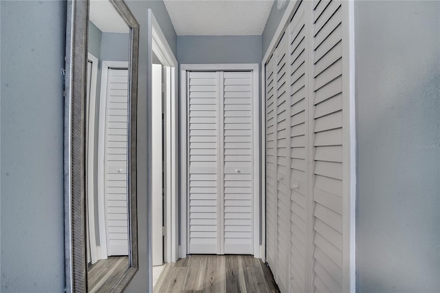 hallway with a textured ceiling and light wood-type flooring