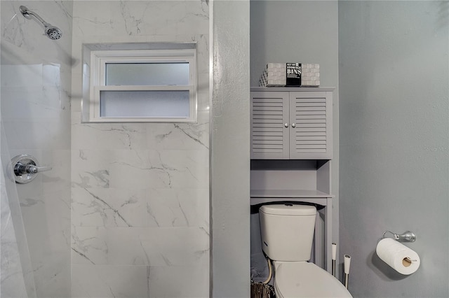 bathroom with a tile shower and toilet