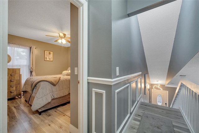 stairs with wood-type flooring, ceiling fan, and a textured ceiling