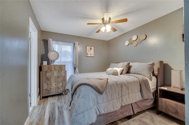 bedroom featuring ceiling fan, light hardwood / wood-style flooring, and a textured ceiling