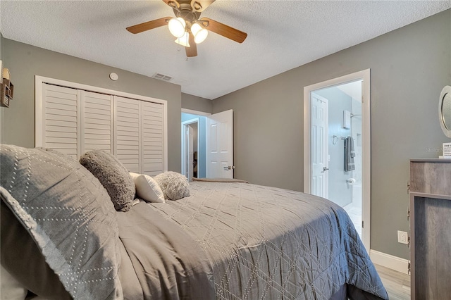 bedroom featuring connected bathroom, a textured ceiling, light wood-type flooring, a closet, and ceiling fan