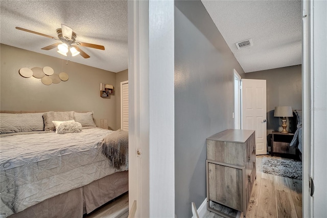 bedroom featuring ceiling fan, a textured ceiling, and light wood-type flooring