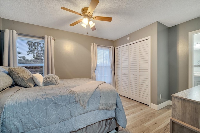 bedroom featuring ceiling fan, light hardwood / wood-style flooring, a closet, and a textured ceiling