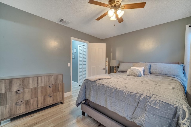 bedroom with ceiling fan, a textured ceiling, and light wood-type flooring