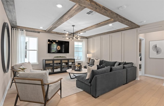 living room featuring light hardwood / wood-style floors, a chandelier, and beamed ceiling