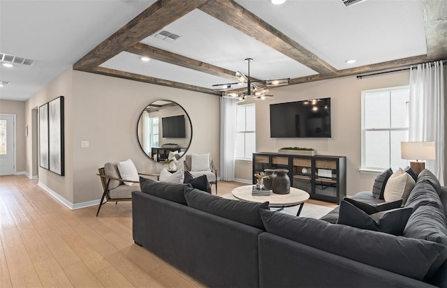 living room with an inviting chandelier, light hardwood / wood-style flooring, and beamed ceiling