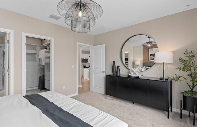 bedroom featuring light carpet, a spacious closet, and a chandelier