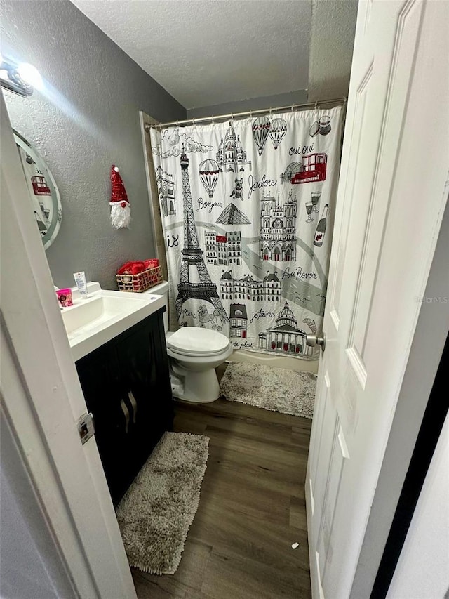 bathroom with hardwood / wood-style floors, vanity, toilet, a textured ceiling, and a shower with shower curtain