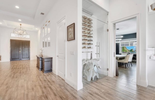 hallway with a raised ceiling and a chandelier