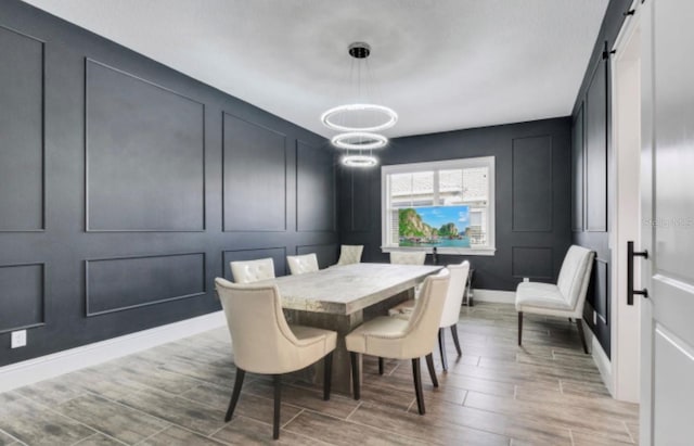 dining space featuring a barn door and a notable chandelier