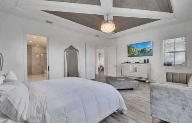 bedroom featuring a raised ceiling, ensuite bathroom, a notable chandelier, and light hardwood / wood-style flooring