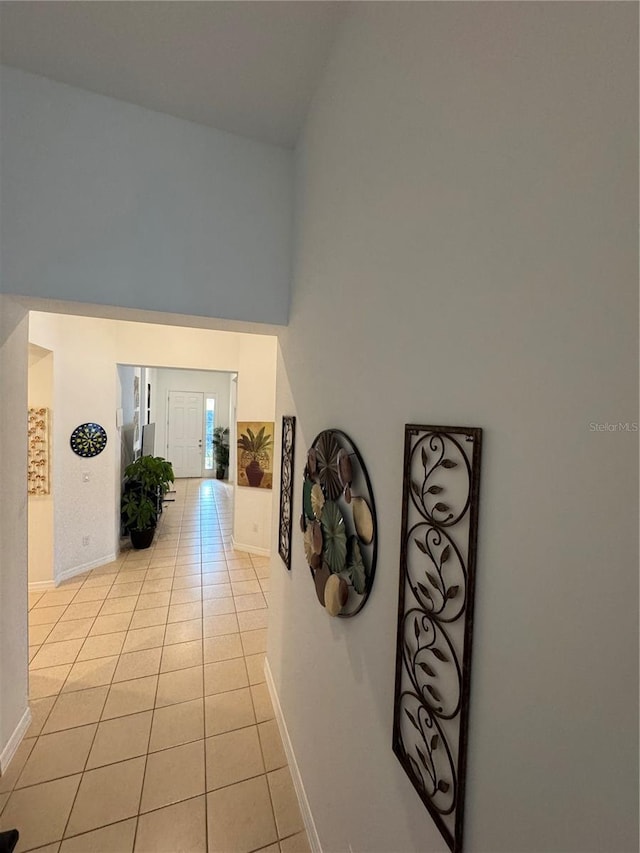 hall featuring light tile patterned floors and a towering ceiling