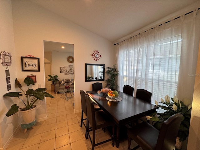 tiled dining space featuring vaulted ceiling