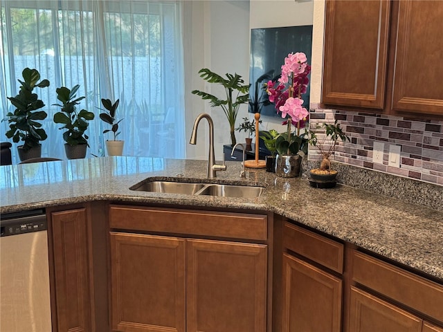 kitchen featuring light stone counters, dishwasher, sink, and backsplash