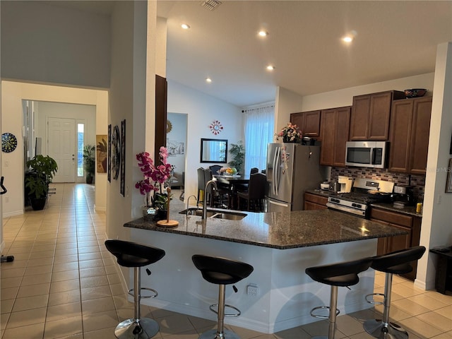 kitchen featuring a breakfast bar, sink, kitchen peninsula, stainless steel appliances, and backsplash