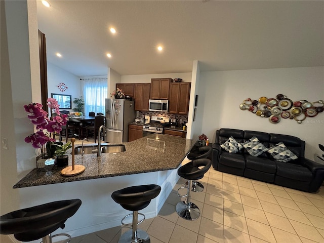 kitchen with decorative backsplash, appliances with stainless steel finishes, kitchen peninsula, and a breakfast bar area