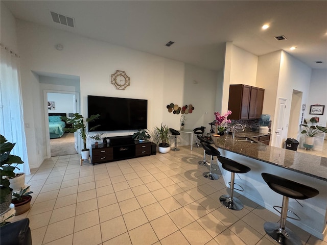 kitchen featuring light tile patterned flooring, sink, a breakfast bar area, kitchen peninsula, and dark stone counters